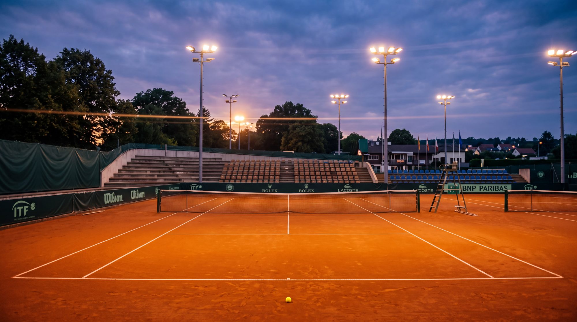 Floodlit clay court at an ITF tournament — the pathway to the pro tour